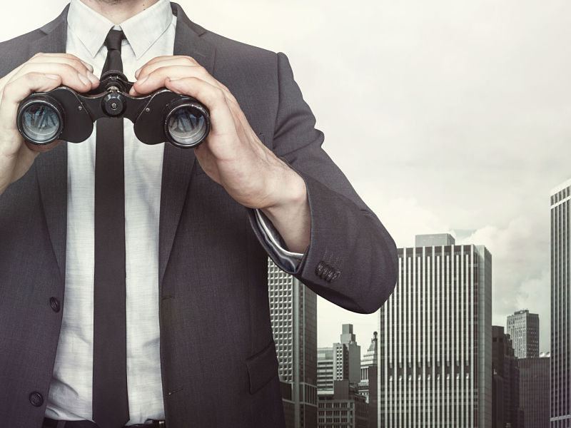 usinessman holding binoculars with tie and shirt on cityscape