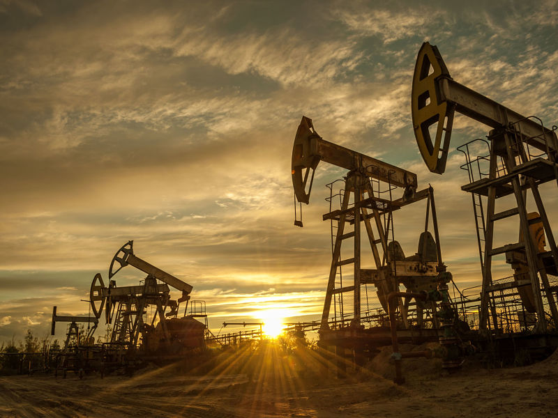 Oil pump jacks at sunset sky background.