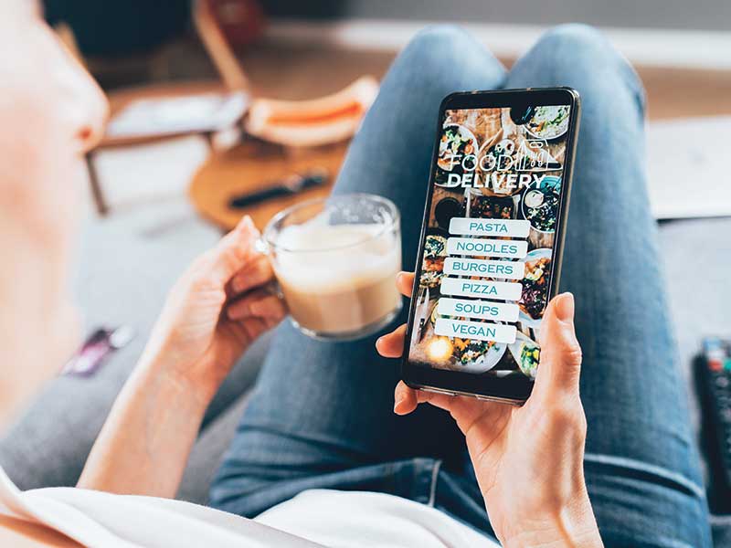 a man, possibly a woman, peruses a dining app while enjoying a machiatto