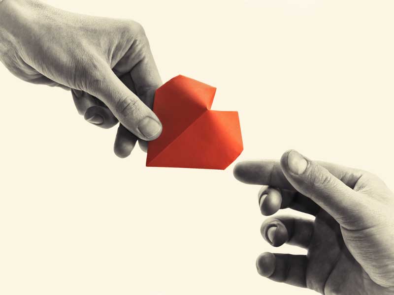 handing a folded heart from one hand to another