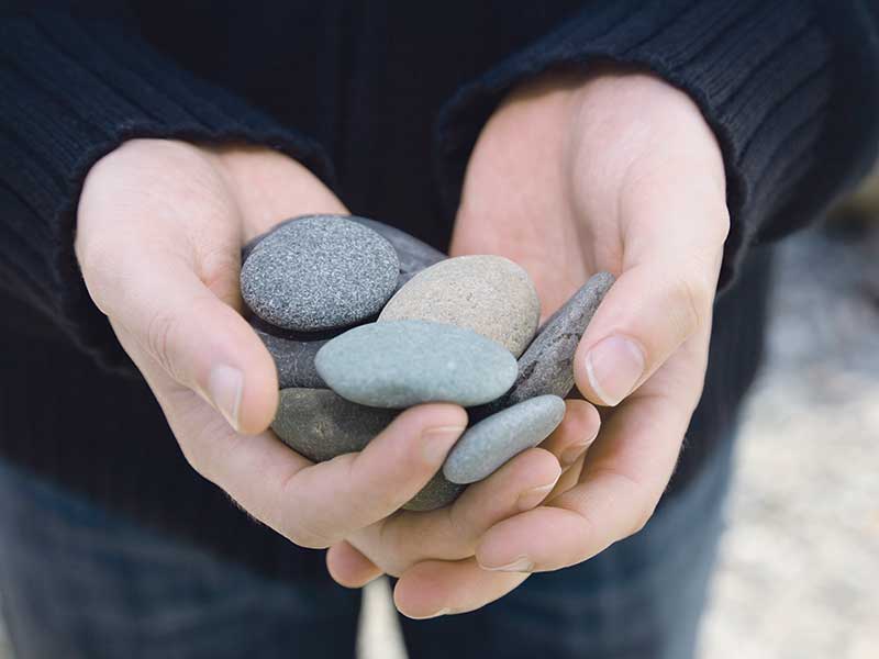 Hand offering rounded pebbles