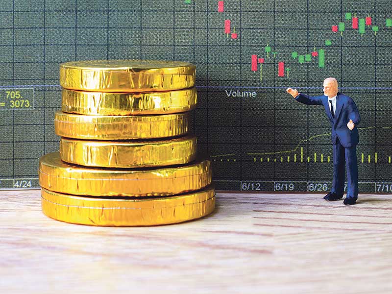 Miniature model man looking giant stack of chocolate coins